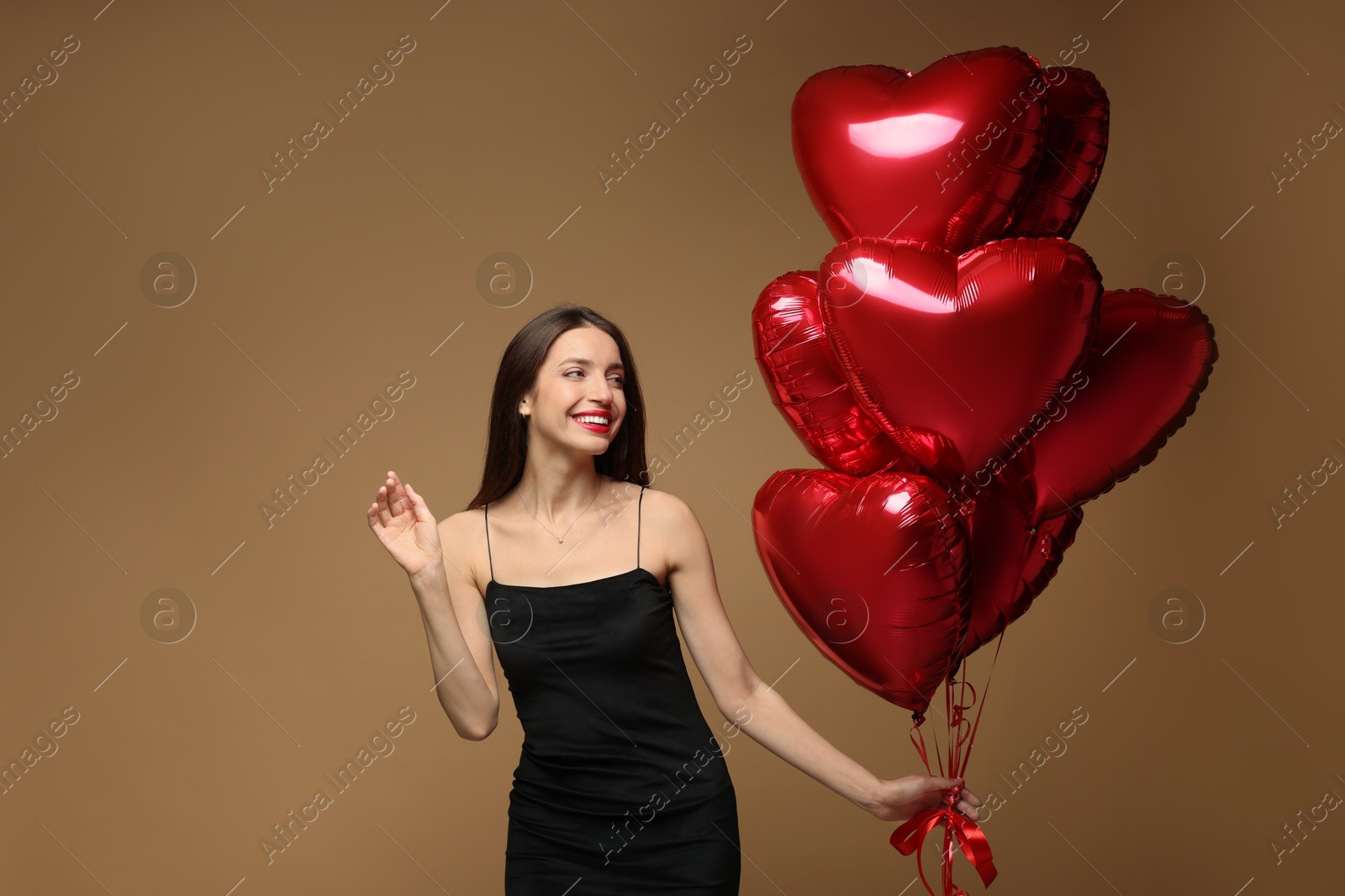 Photo of Happy Valentine's Day. Beautiful woman with heart shaped balloons on brown background