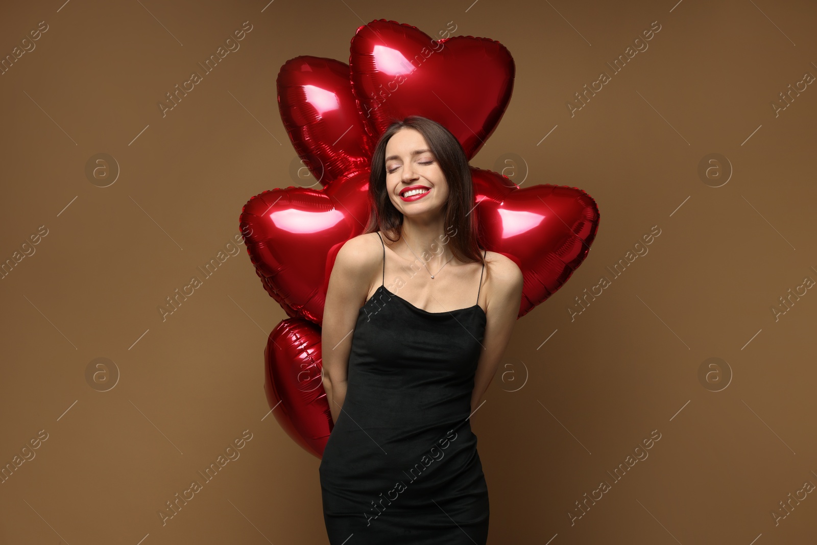 Photo of Happy Valentine's Day. Beautiful woman with heart shaped balloons on brown background