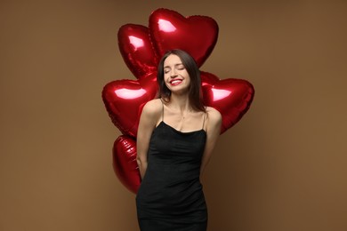 Photo of Happy Valentine's Day. Beautiful woman with heart shaped balloons on brown background