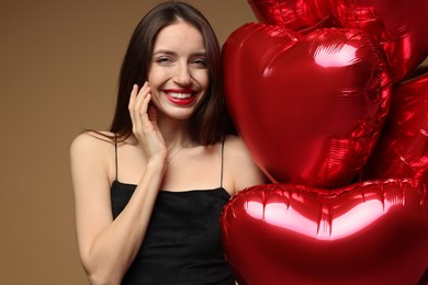 Photo of Happy Valentine's Day. Beautiful woman with heart shaped balloons on brown background