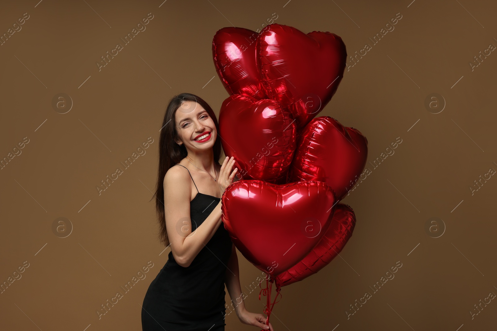 Photo of Happy Valentine's Day. Beautiful woman with heart shaped balloons on brown background