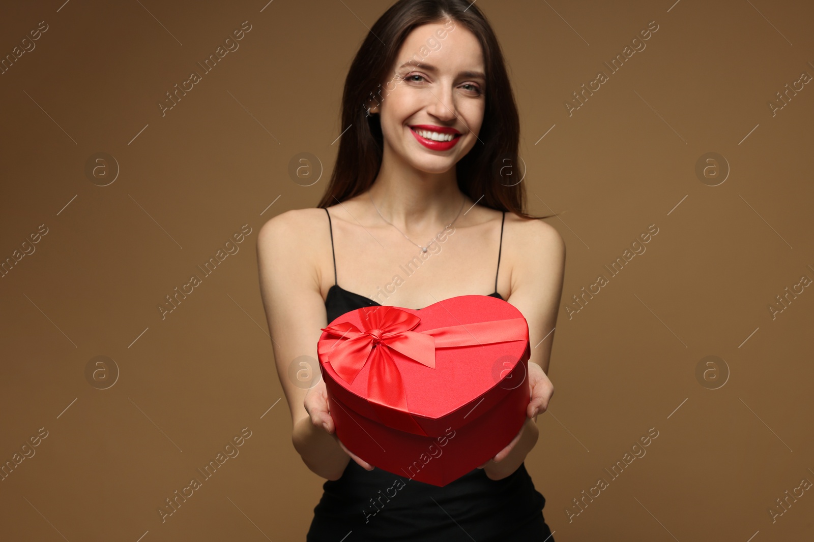 Photo of Happy Valentine's Day. Beautiful woman with heart shaped gift box on brown background