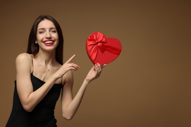 Photo of Happy Valentine's Day. Beautiful woman with heart shaped gift box on brown background. Space for text