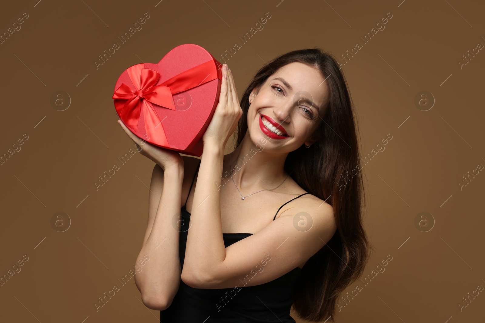 Photo of Happy Valentine's Day. Beautiful woman with heart shaped gift box on brown background