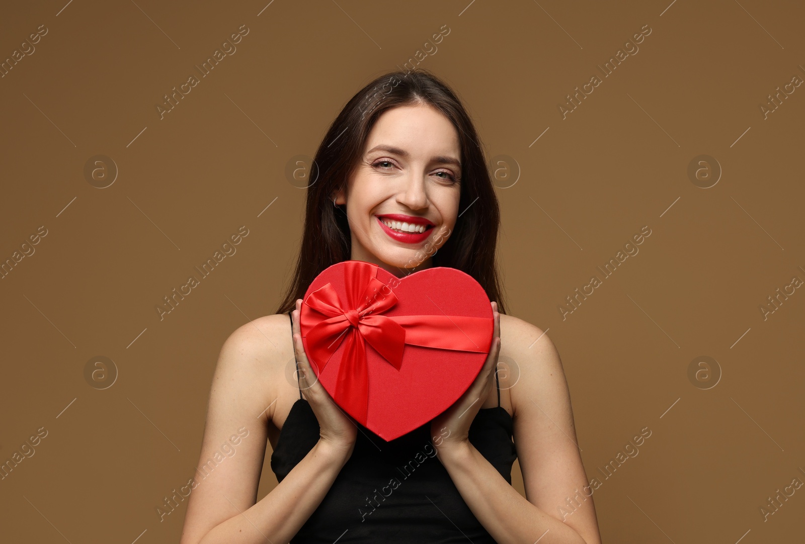 Photo of Happy Valentine's Day. Beautiful woman with heart shaped gift box on brown background