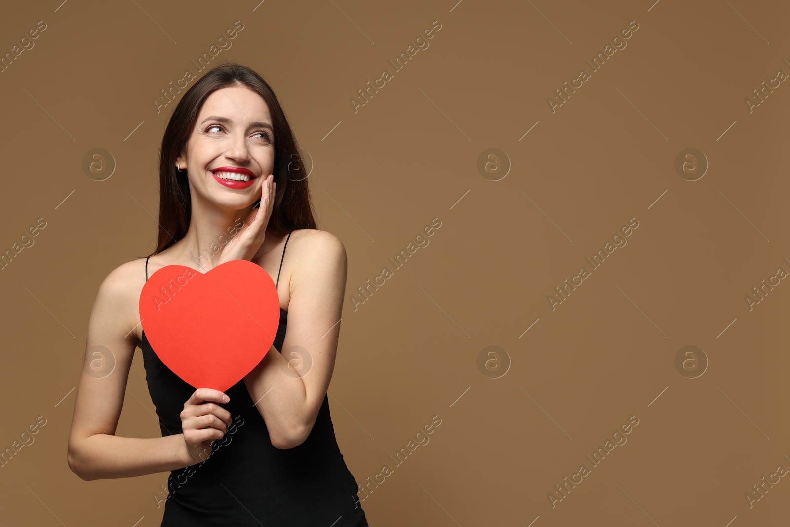 Photo of Happy Valentine's Day. Beautiful woman with paper heart on brown background. Space for text