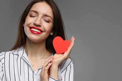 Photo of Happy Valentine's Day. Beautiful woman with paper heart on grey background. Space for text