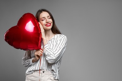 Photo of Happy Valentine's Day. Beautiful woman with heart shaped balloon on grey background. Space for text