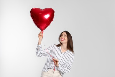 Photo of Happy Valentine's Day. Beautiful woman with heart shaped balloon on white background