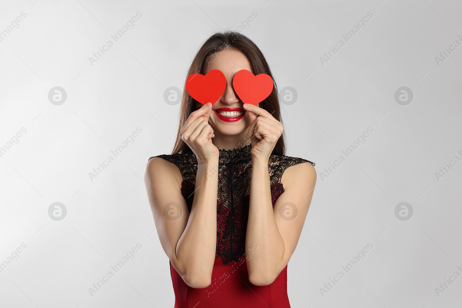 Photo of Happy Valentine's Day. Woman covering her face with paper hearts on white background