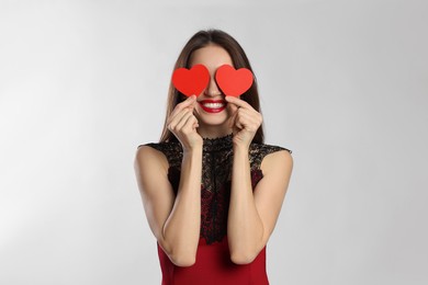 Photo of Happy Valentine's Day. Woman covering her face with paper hearts on white background