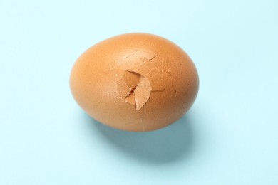 One egg with cracked shell on light background, above view