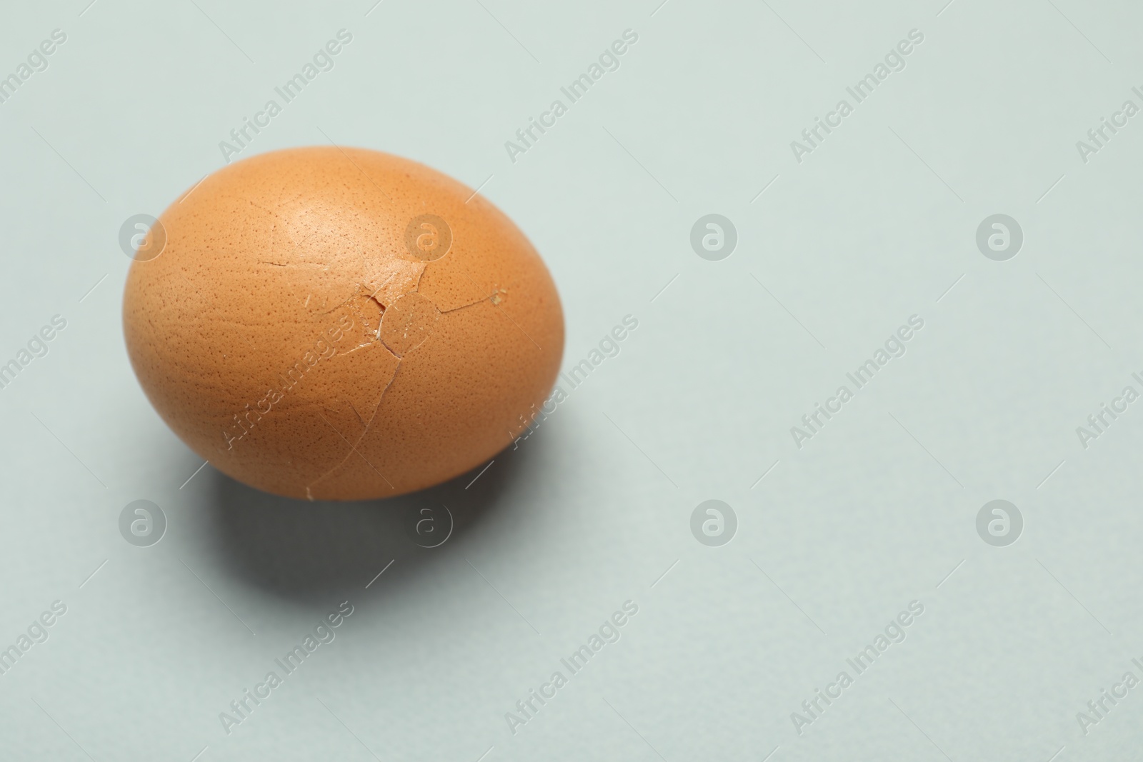 Photo of One egg with cracked shell on grey background. Space for text