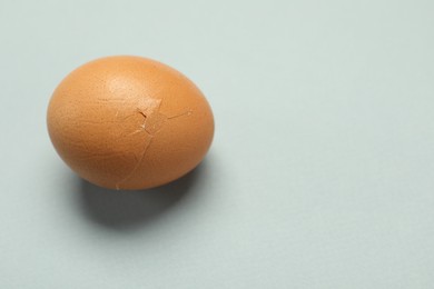 Photo of One egg with cracked shell on grey background. Space for text