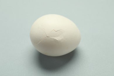 One egg with cracked shell on grey background, closeup