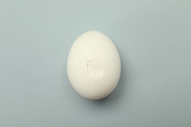 Photo of One egg with cracked shell on grey background, top view