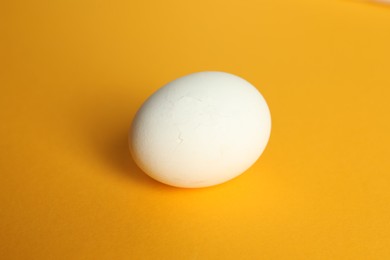 One egg with cracked shell on orange background