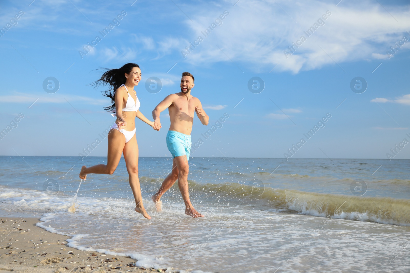 Photo of Happy young couple running together on beach