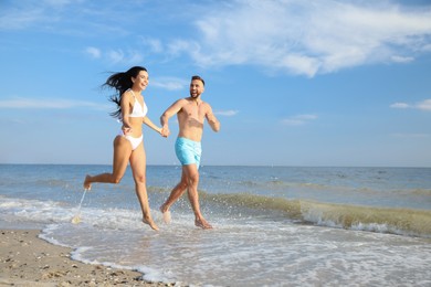 Photo of Happy young couple running together on beach