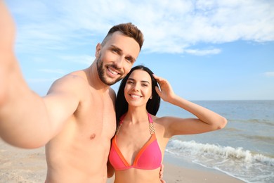 Photo of Happy young couple taking selfie on beach