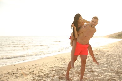 Happy young couple having fun on beach on sunny day