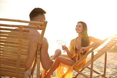 Photo of Romantic couple drinking wine together on beach at sunset