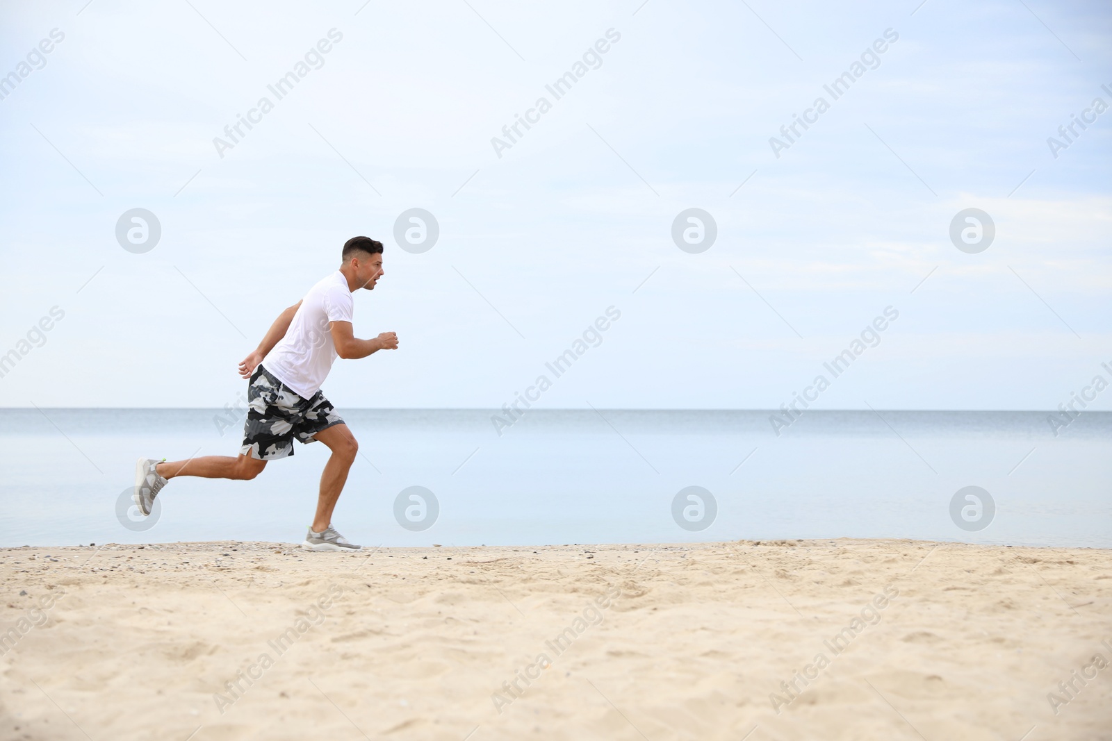 Photo of Muscular man running on beach, space for text. Body training