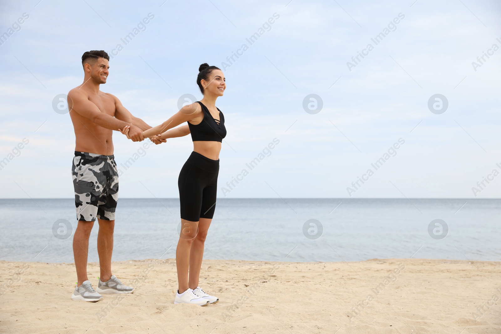 Photo of Couple doing exercise together on beach, space for text. Body training