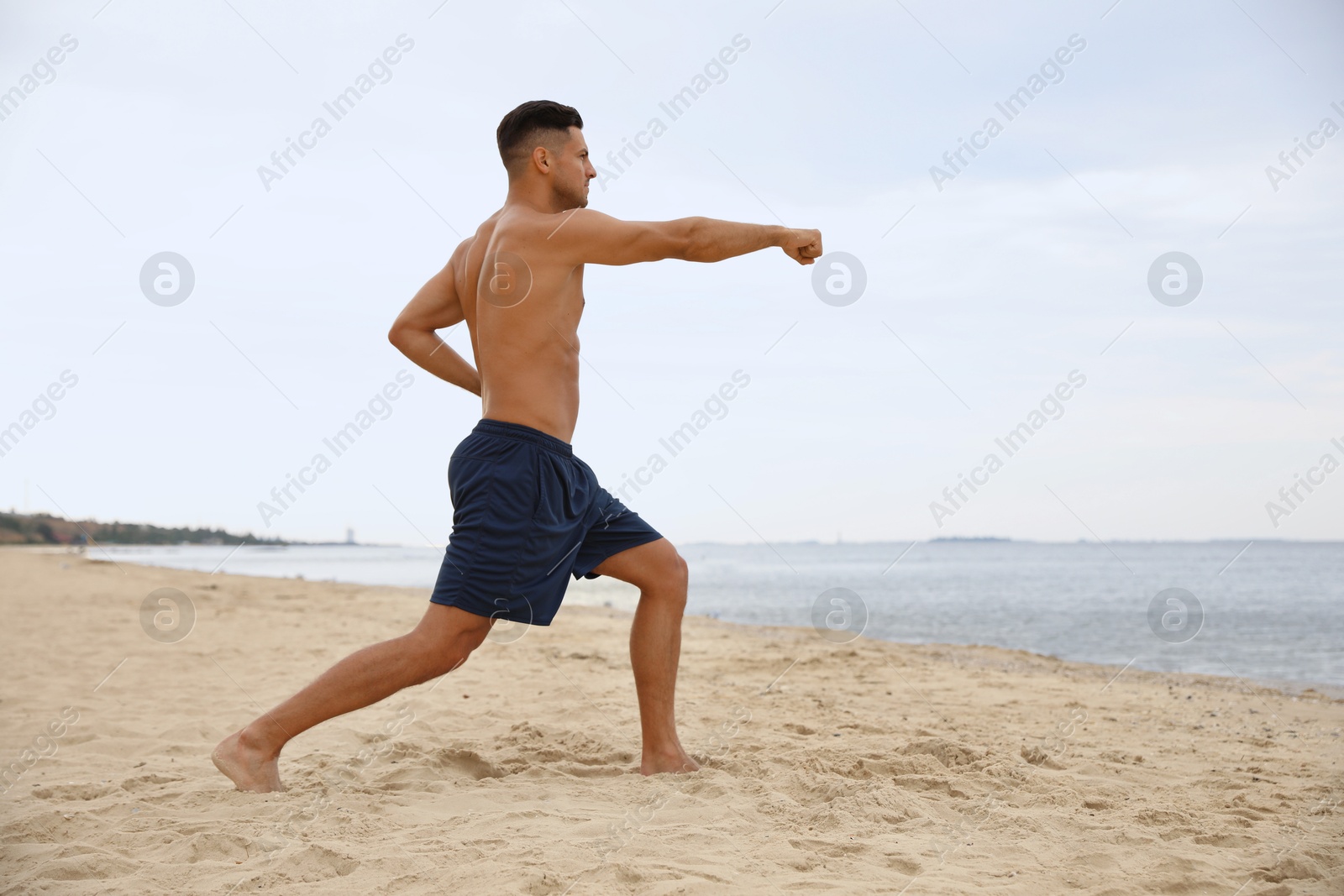 Photo of Muscular man doing exercise on beach. Body training