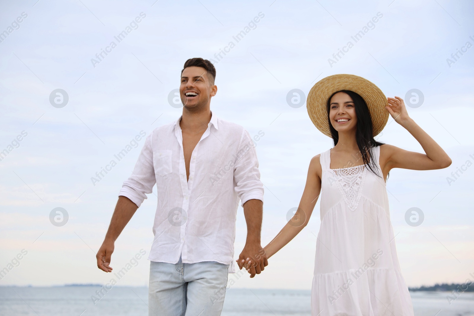 Photo of Lovely couple holding hands while walking near sea