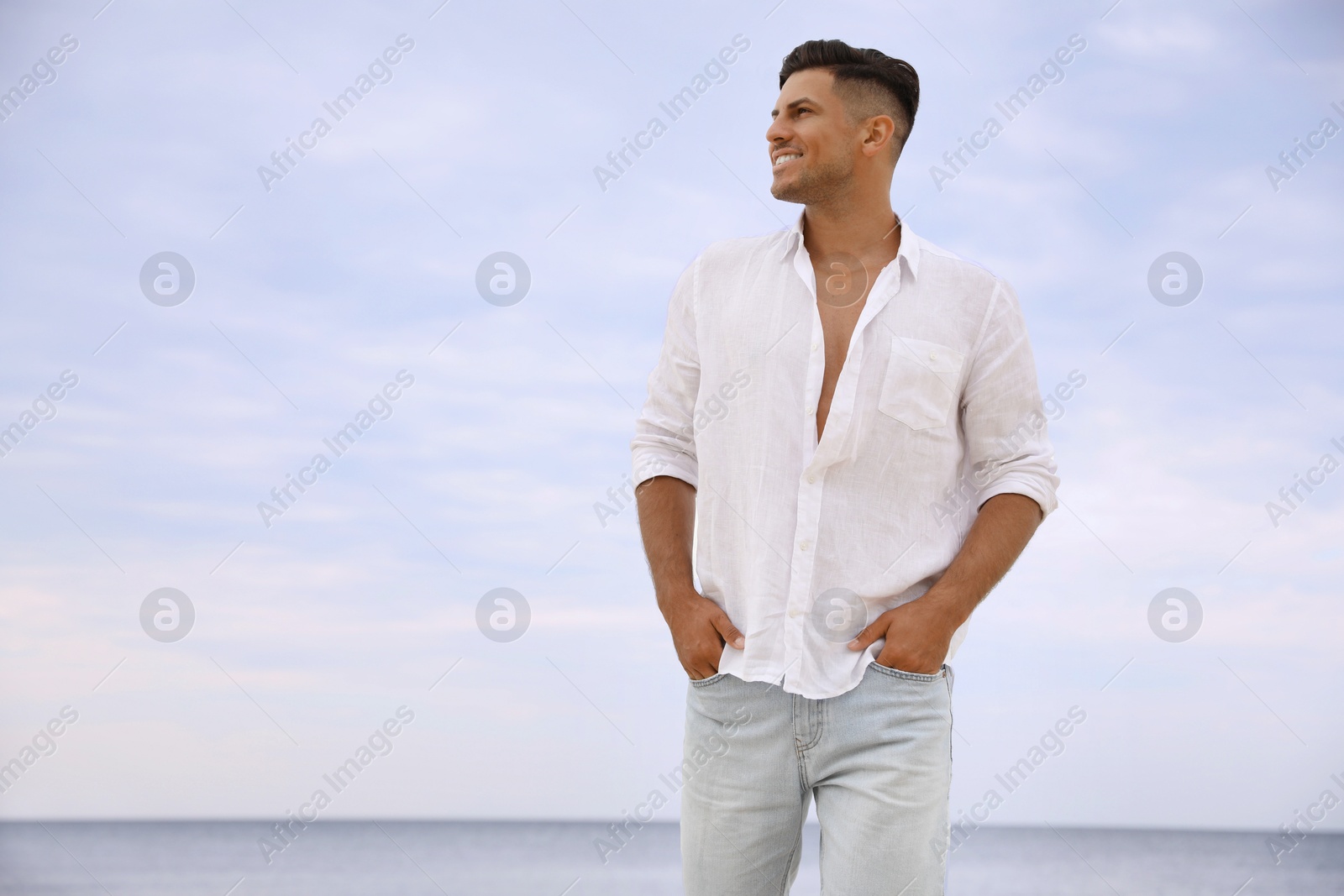 Photo of Handsome man on beach near sea. Space for text