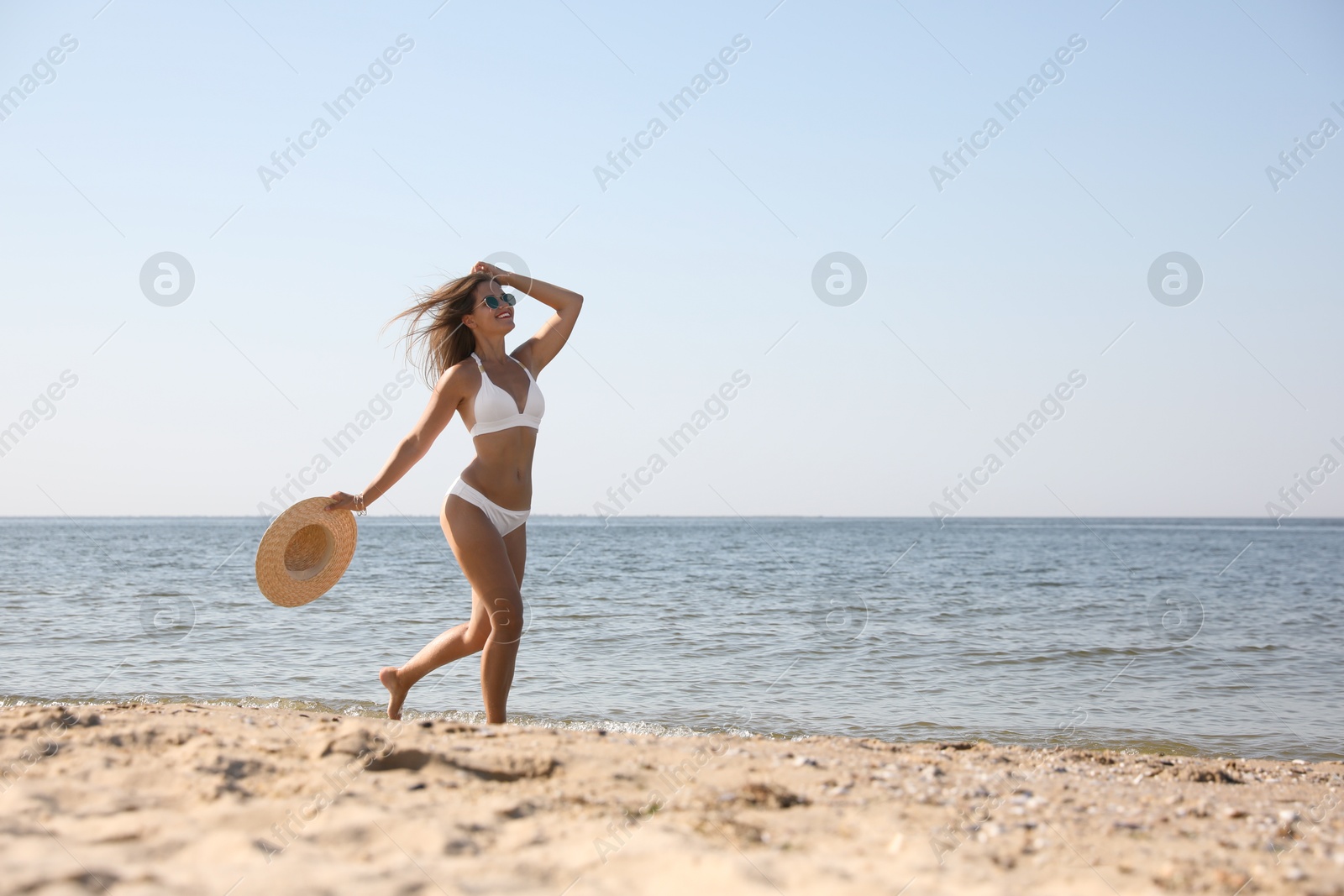 Photo of Young woman with beautiful body on sandy beach. Space for text