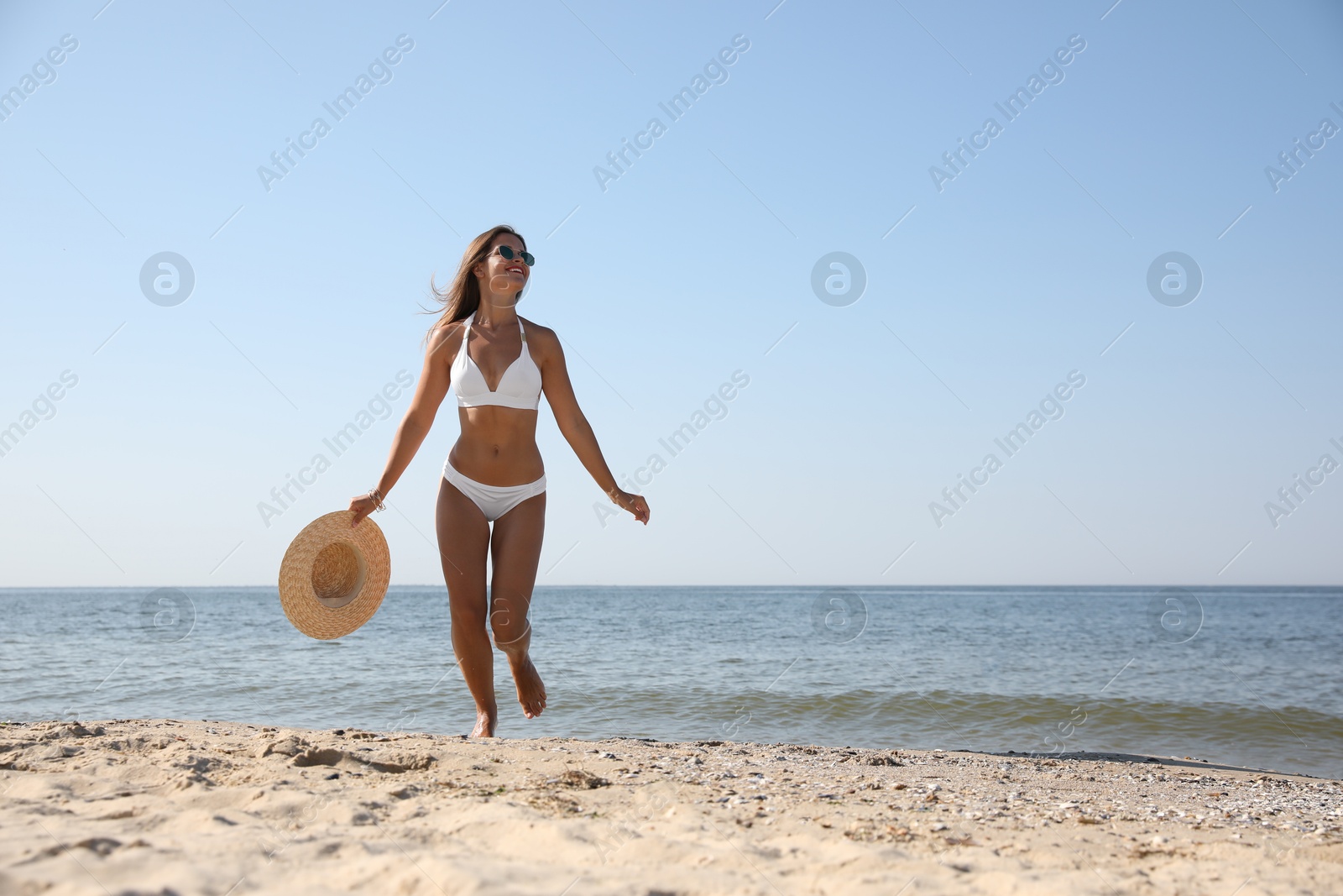 Photo of Young woman with beautiful body on sandy beach. Space for text