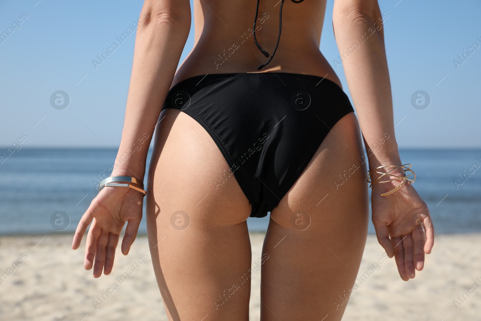 Photo of Young woman with beautiful body on beach, closeup