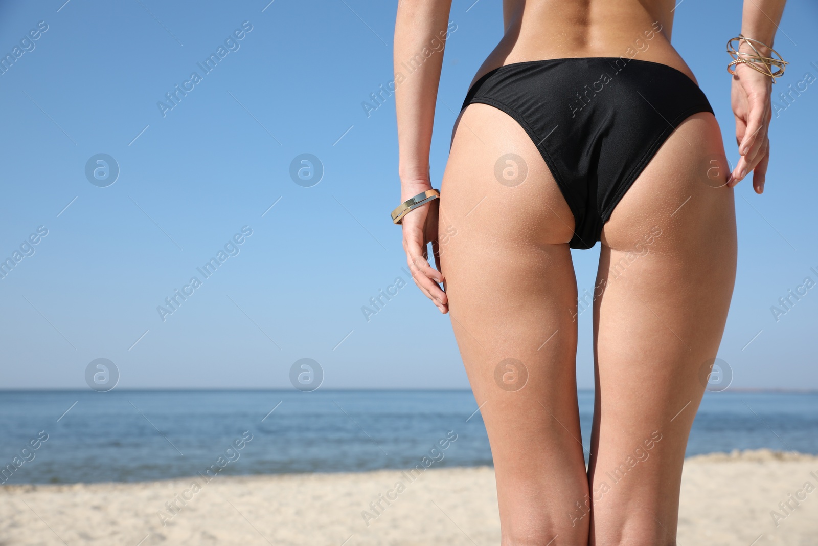 Photo of Young woman with beautiful body on beach, closeup. Space for text