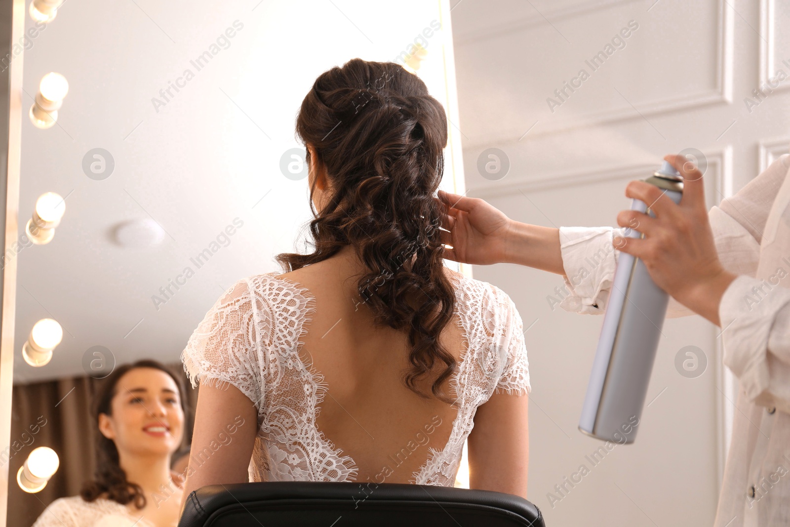 Photo of Stylist working with client in salon, making wedding hairstyle