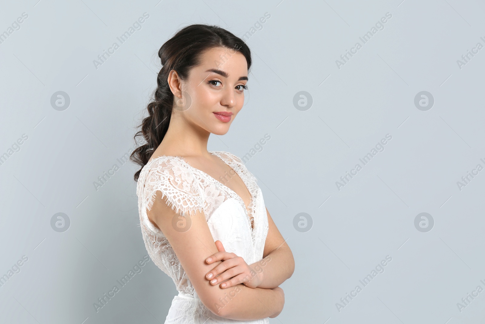 Photo of Young bride with beautiful wedding hairstyle on light grey background. Space for text