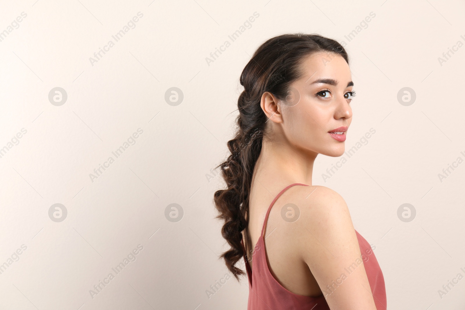 Photo of Young woman with beautiful hairstyle on beige background. Space for text