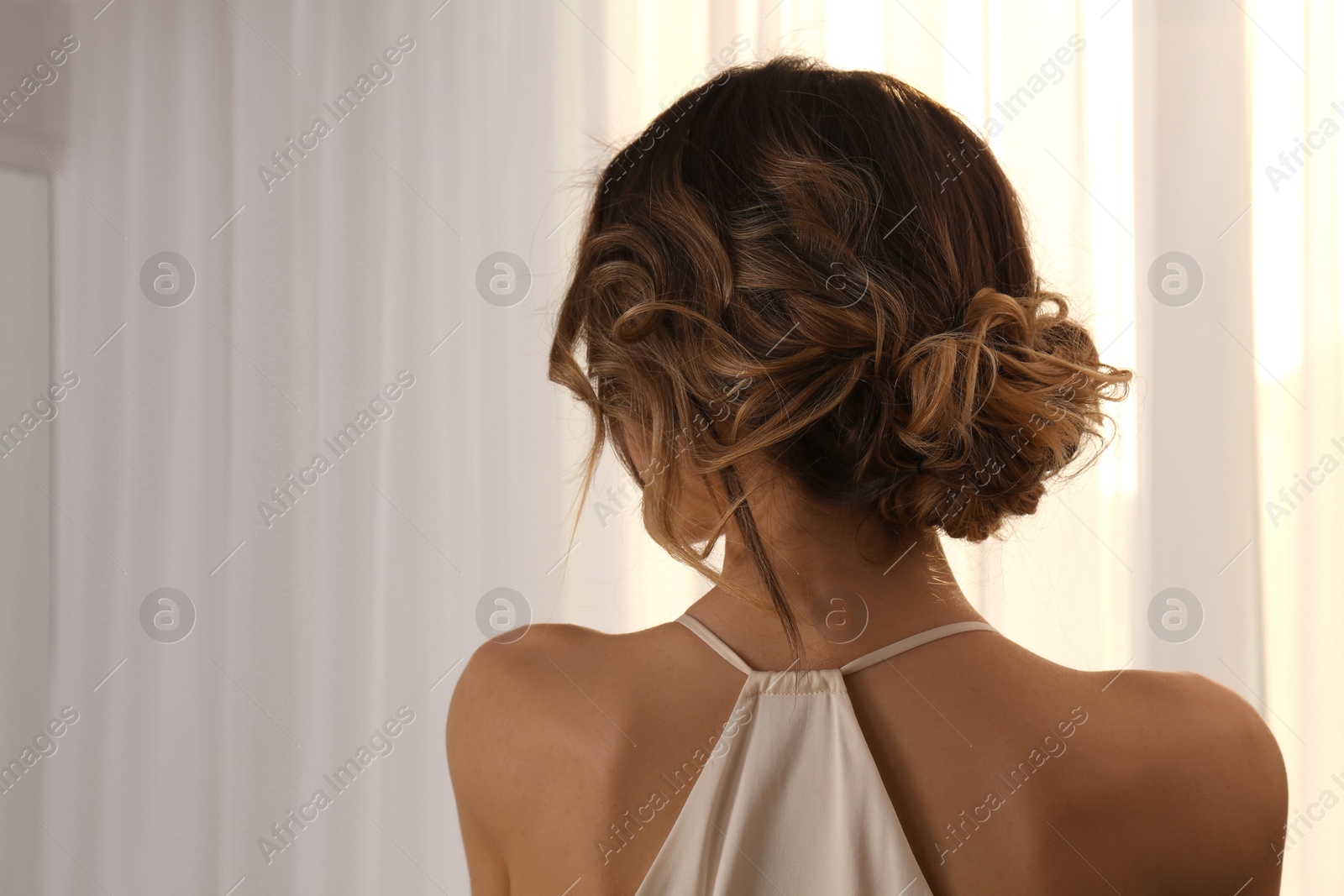 Photo of Young woman with beautiful hairstyle near window indoors. Space for text