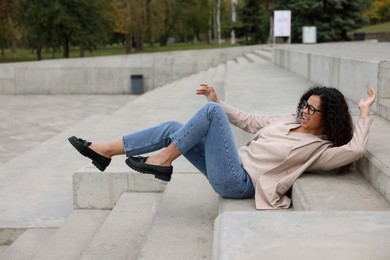 Photo of Injured woman on stairs outdoors after fall. Dangerous accident