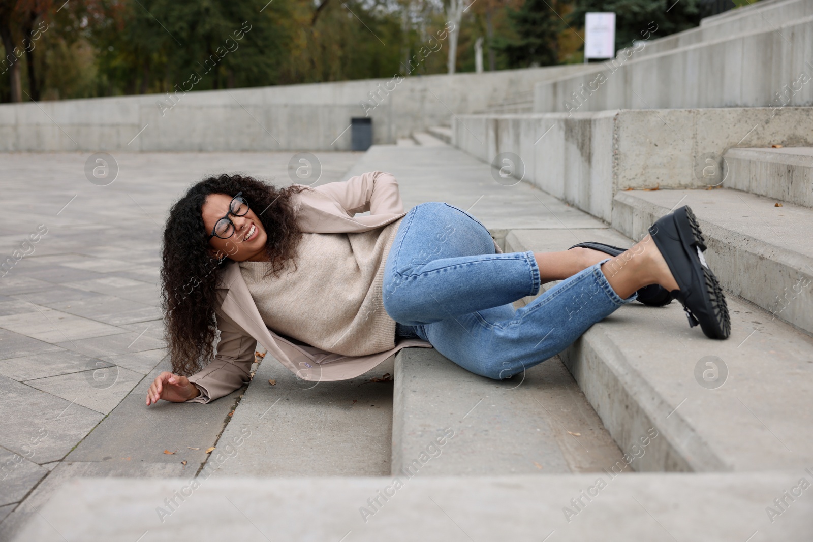 Photo of Injured woman on stairs outdoors after fall. Dangerous accident