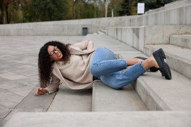 Photo of Injured woman on stairs outdoors after fall. Dangerous accident