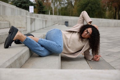 Photo of Injured woman on stairs outdoors after fall. Dangerous accident