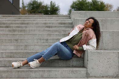 Photo of Woman with injured back on stairs outdoors after fall. Dangerous accident