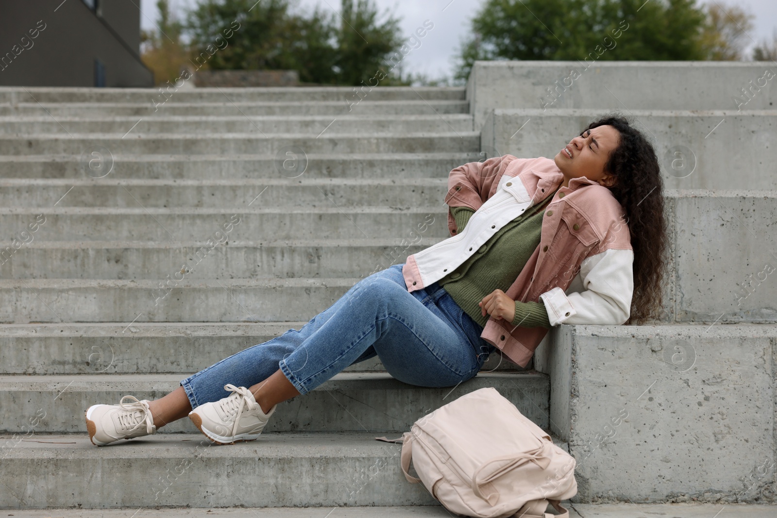 Photo of Woman with injured back on stairs outdoors after fall. Dangerous accident