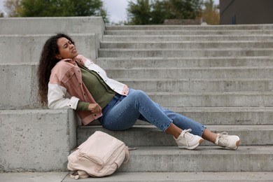 Photo of Woman with injured back on stairs outdoors after fall. Dangerous accident