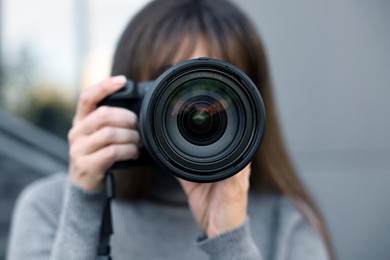 Photo of Professional photographer taking picture with camera outdoors, selective focus