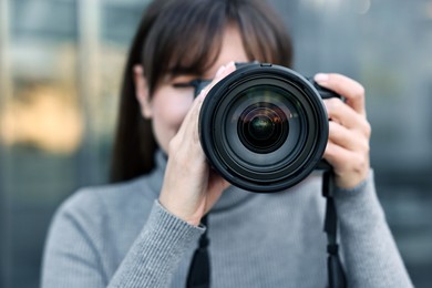 Photo of Professional photographer taking picture with camera outdoors, selective focus