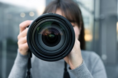 Photo of Professional photographer taking picture with camera outdoors, selective focus