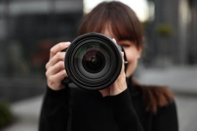 Photo of Professional photographer taking picture with camera outdoors, selective focus